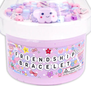 Container of pastel-colored friendship bracelet slime with a plush cloud toy on top.
