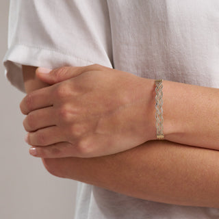 Gold bracelet on a person's wrist with a neutral background