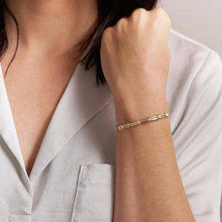 Gold bracelet on a person's wrist with a neutral background