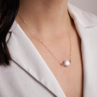 Pearl necklace worn by a person with a white background