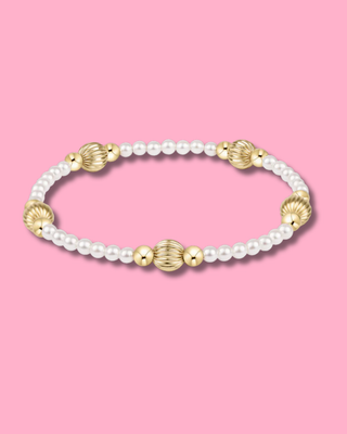 Bracelet with pearls and gold beads on a pink background