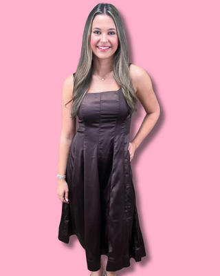 Woman wearing a dark brown strapless dress against a pink background