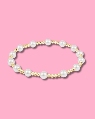 Pearl and gold beaded bracelet on a pink background