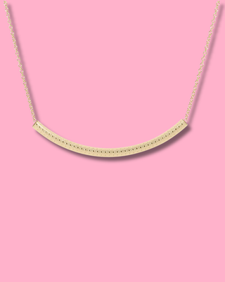 Gold necklace on a pink background