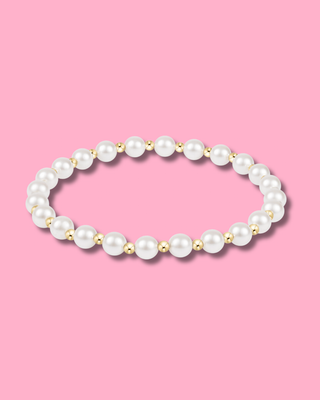 Pearl bracelet with gold accents on a pink background