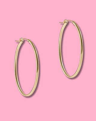 Gold hoop earrings on a pink background