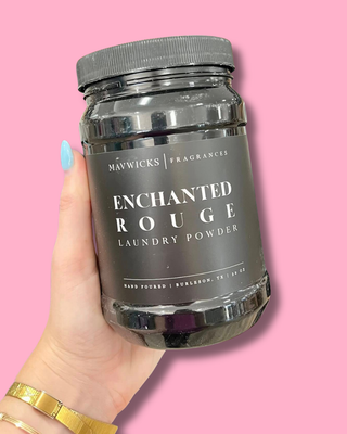 Jar of Mawicks Enchanted Rouge laundry powder held by a hand against a pink background