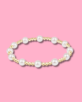 Pearl and gold beaded bracelet on a pink background