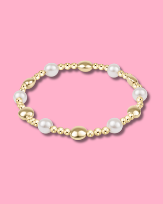 Bracelet with gold and pearl beads on a pink background