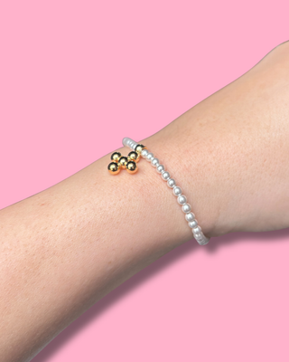 Two bracelets on a wrist against a pink background