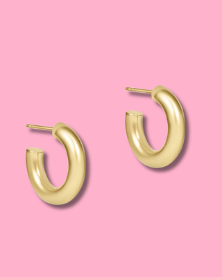 Gold hoop earrings on a pink background