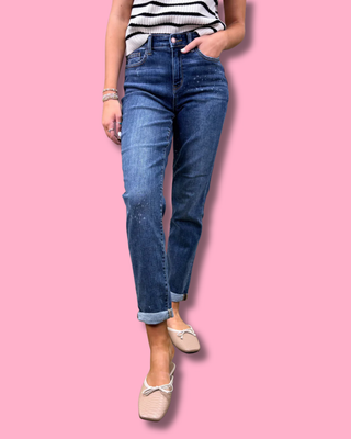 Person wearing blue jeans and a striped top on a pink background