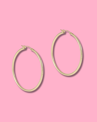 Gold hoop earrings on a pink background