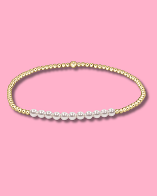 Gold and pearl bracelet on a pink background
