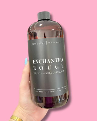 Bottle of Maywicks Enchanted Rouge laundry detergent held against a pink background