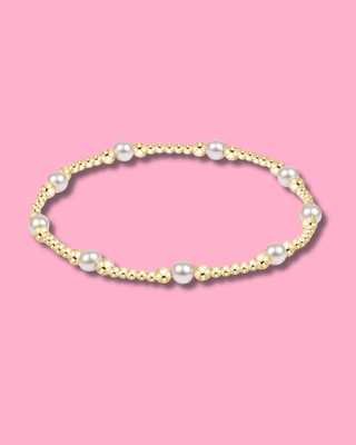 Gold and pearl bracelet on a pink background