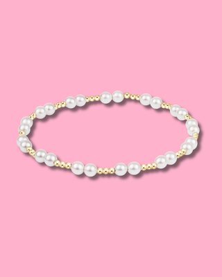 Pearl necklace with gold accents on a pink background