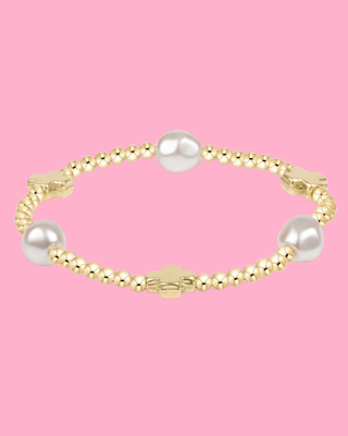 Gold bracelet with pearls on a pink background