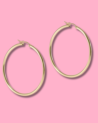 Gold hoop earrings on a pink background
