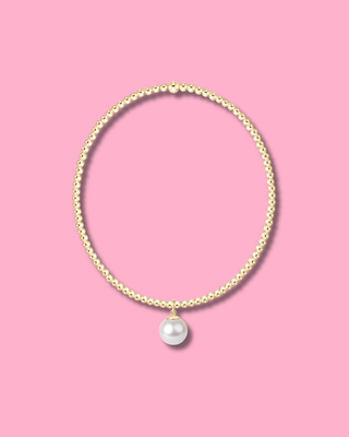 Pearl necklace with a gold chain on a pink background