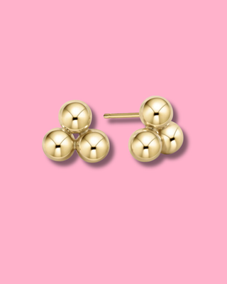 Gold earrings on a pink background
