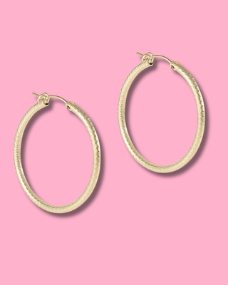 Gold hoop earrings on a pink background
