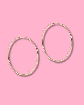 Gold hoop earrings on a pink background