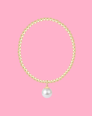 Gold beaded necklace with a pearl pendant on a pink background
