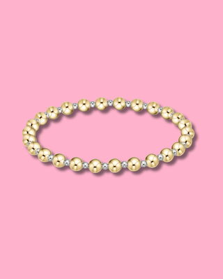 Gold and silver beaded bracelet on a pink background