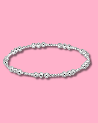 Silver beaded bracelet on a pink background