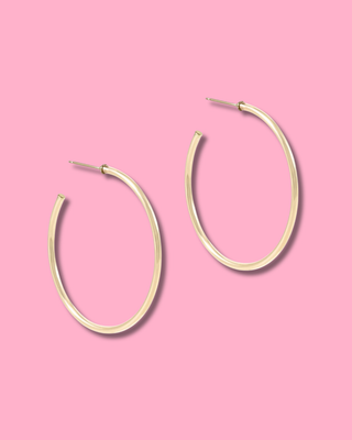 Gold hoop earrings on a pink background