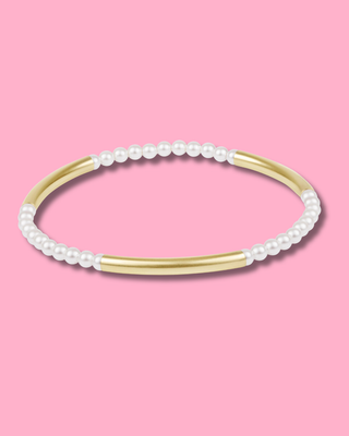 Pearl and gold bracelet on a pink background