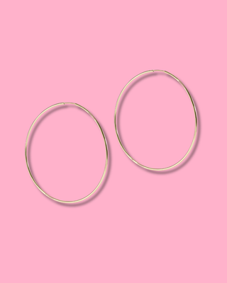 Gold hoop earrings on a pink background