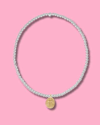 Pearl necklace with a gold cross pendant on a pink background