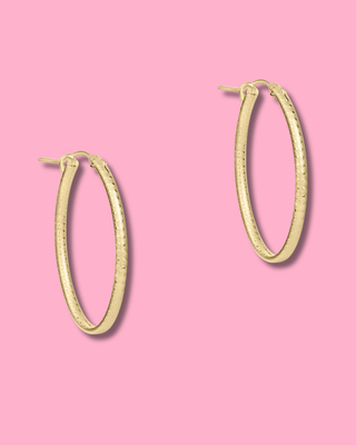 Gold hoop earrings on a pink background
