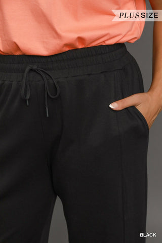 Black plus-size pants worn with an orange top on a gray background