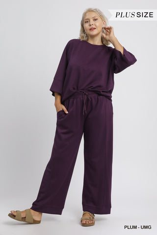 Woman wearing a plum-colored outfit on a white background with 'Plus Size' text.