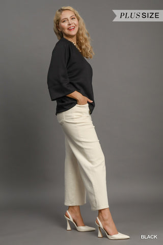 Woman wearing a black top and white pants on a gray background with 'Plus Size' text.
