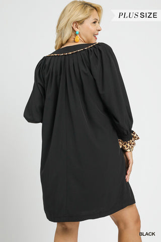 Woman wearing a black dress with leopard print cuffs on a white background
