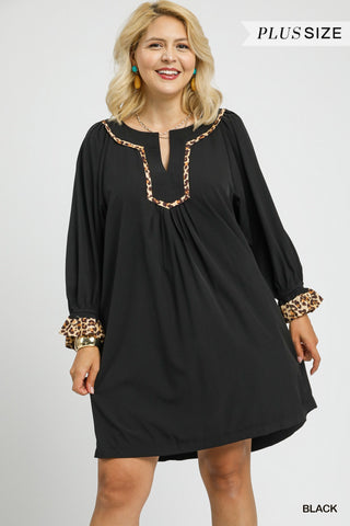 Woman wearing a black dress with leopard print accents on a white background