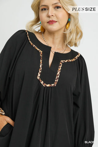 Woman wearing a black dress with leopard print trim on a white background