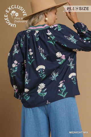 Woman wearing a navy floral blouse with wide-brimmed hat against a brown background