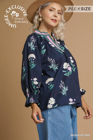 Woman wearing a navy blue blouse with floral embroidery on a beige background