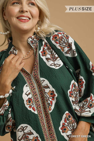 Woman wearing a forest green plus-size dress with floral patterns on a beige background