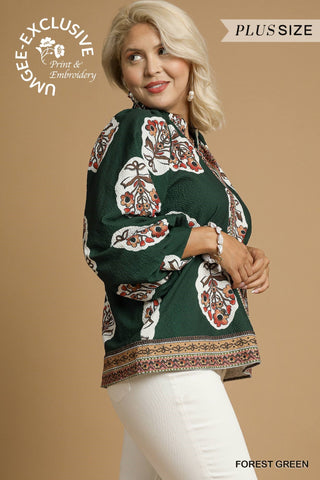 Woman wearing a forest green blouse with floral patterns on a beige background