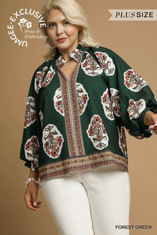 Woman wearing a forest green blouse with floral patterns on a beige background