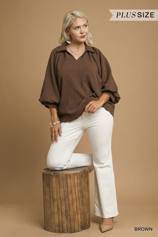 Woman wearing a brown blouse and white pants on a beige background
