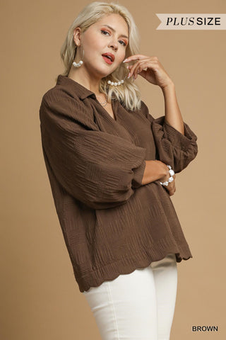 Woman wearing a brown plus-size blouse against a beige background