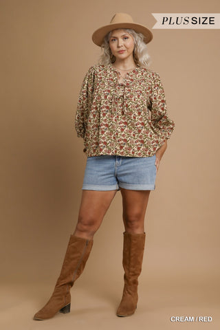 Woman wearing a floral blouse, denim shorts, and brown knee-high boots on a beige background