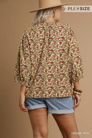 Person wearing a floral blouse and denim shorts against a beige background